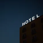 low-angle photo of Hotel lighted signage on top of brown building during nighttime