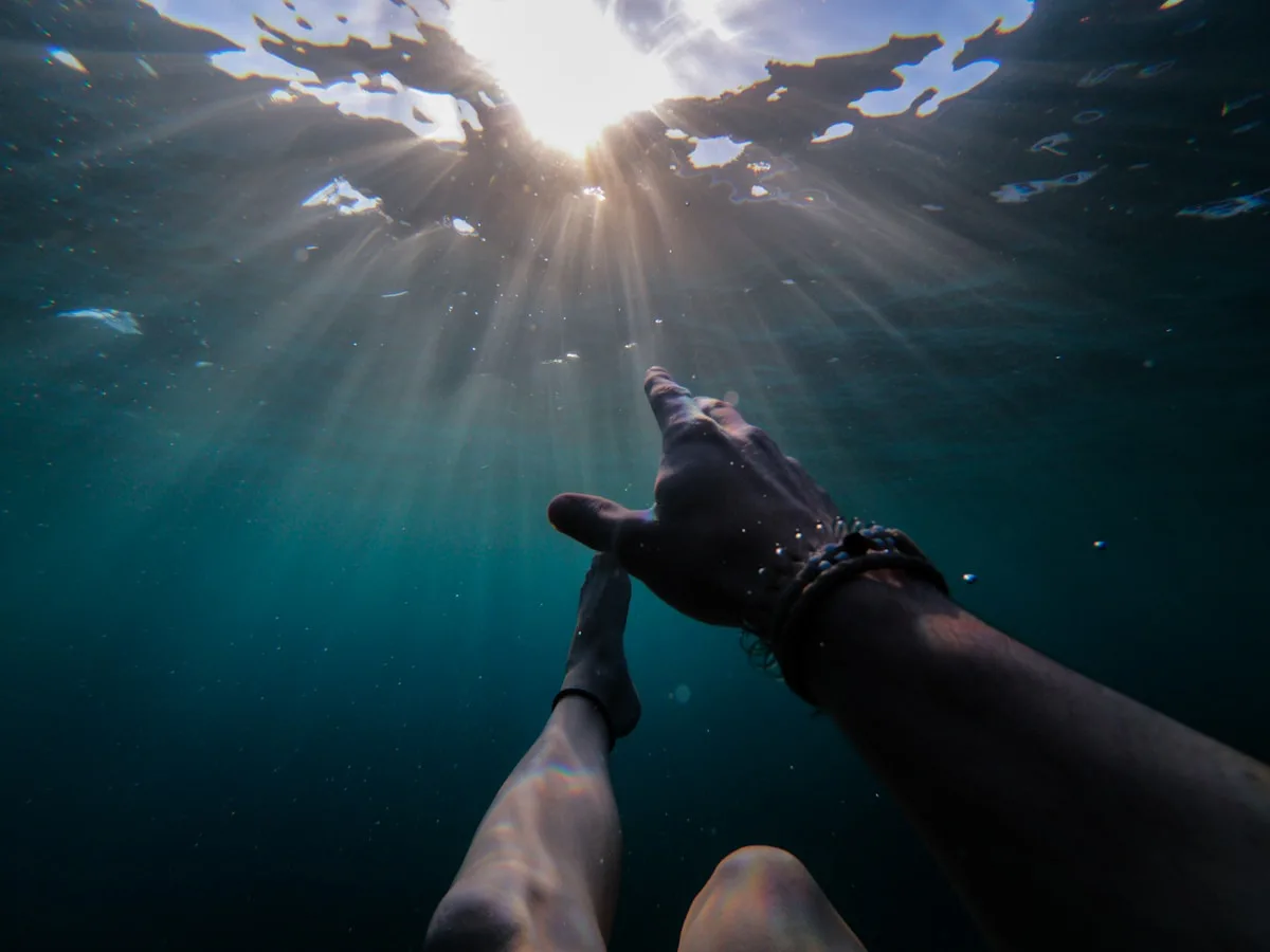 underwater photography of person soaking under sun rays